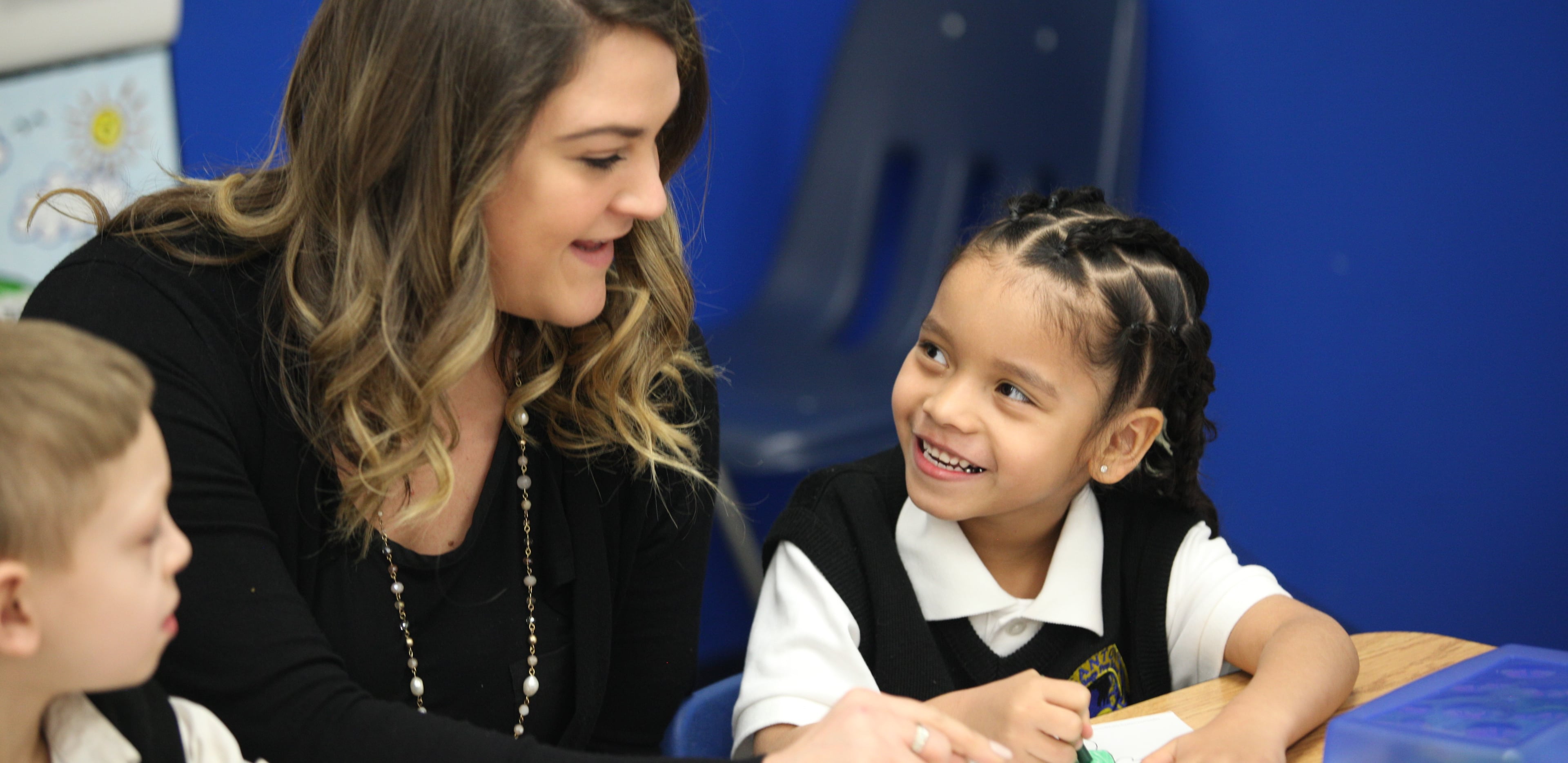 Adult and child smiling and interacting at a desk.